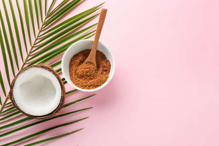 Sweet coconut and bowl of sugar on color background