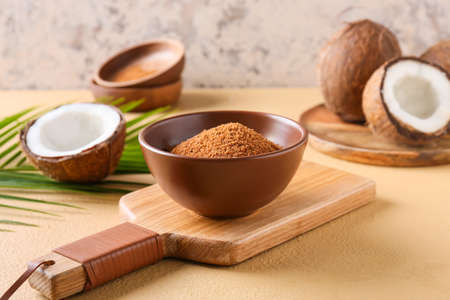 Bowl of sugar and sweet coconuts on color backgroundの写真素材