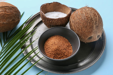 Sweet coconuts and bowl of sugar on color backgroundの写真素材