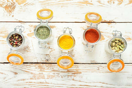 Jars with different spices on light wooden backgroundの写真素材