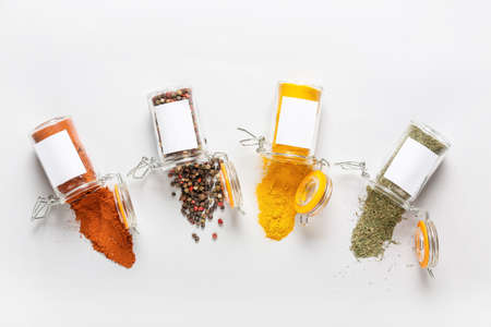 Overturned jars with different spices on white backgroundの写真素材
