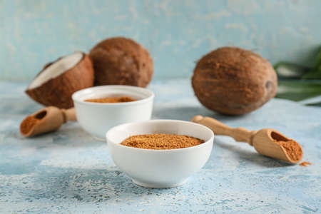 Bowls of sugar and sweet coconuts on color backgroundの写真素材