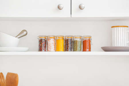 Jars with different spices on shelf in kitchenの写真素材