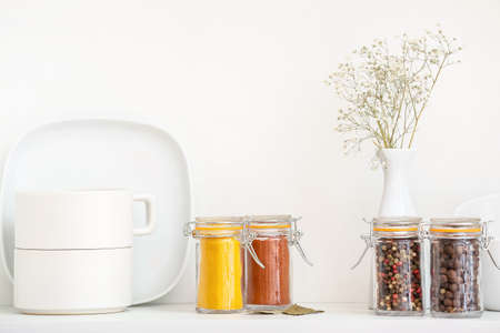 Jars with different spices and dishes on shelf in kitchenの写真素材