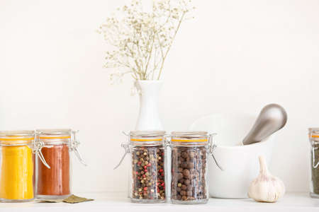 Jars with different spices and mortar on table in kitchenの写真素材