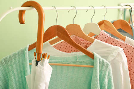 Rack with stylish clothes and umbrella near color wall, closeupの写真素材