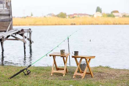 Fishing rod, bucket and stools on river bankの写真素材