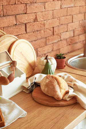 Board with tasty fresh bread and cooking utensils on kitchen tableの写真素材