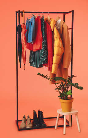 Rack with stylish clothes, shoes and umbrellas on color backgroundの写真素材