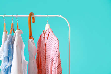Rack with stylish clothes and umbrella on color backgroundの写真素材