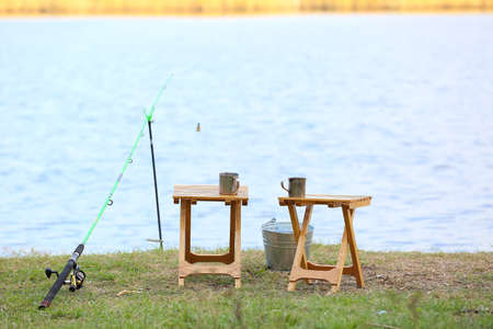 Fishing rod, bucket and stools on river bankの写真素材