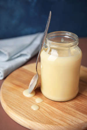 Jar with sweet condensed milk on color backgroundの写真素材