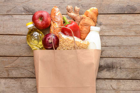 Paper bag with different products on wooden backgroundの写真素材