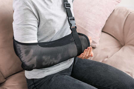 Young woman with broken arm at homeの写真素材