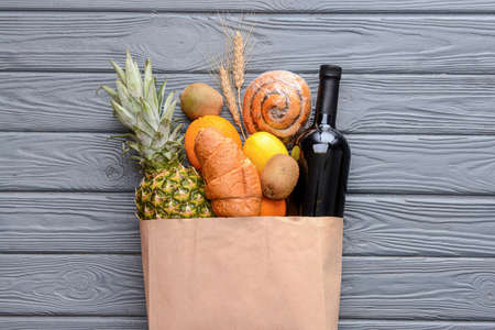 Paper bag with different products on wooden backgroundの写真素材