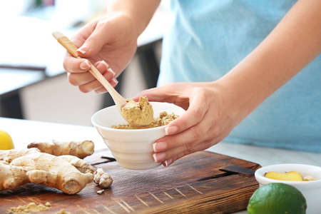 Woman with ginger powder on table in kitchenの写真素材