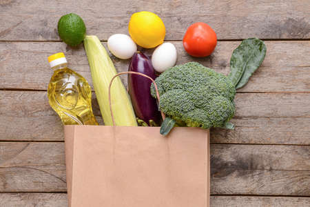 Paper bag with different products on wooden backgroundの写真素材