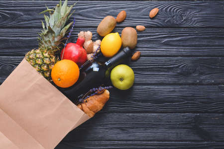 Paper bag with different products on dark wooden backgroundの写真素材