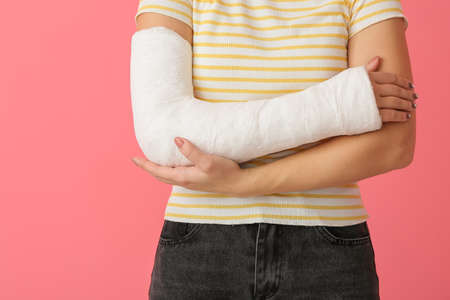 Young woman with broken arm on color backgroundの写真素材