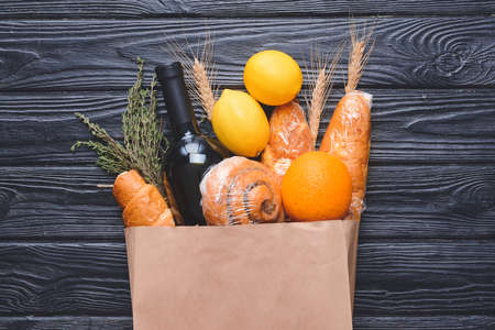 Paper bag with different products on dark wooden backgroundの写真素材