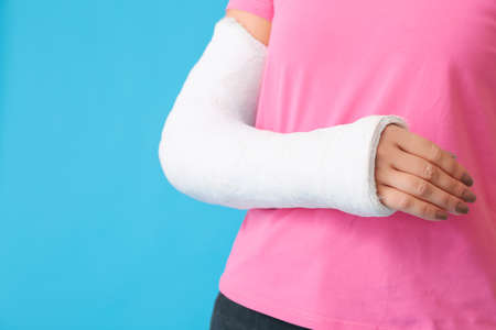 Young woman with broken arm on color background, closeupの写真素材