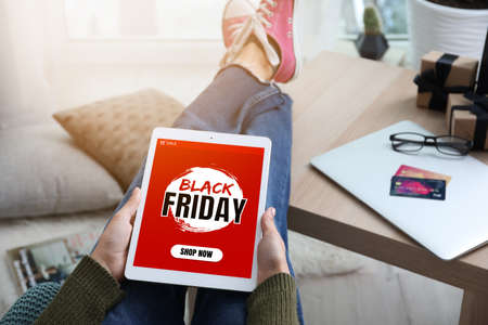 Young woman with tablet computer shopping online on Black Friday at homeの写真素材