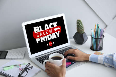 Young woman with laptop shopping online on Black Friday in officeの写真素材