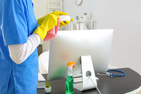Male janitor cleaning computer in office