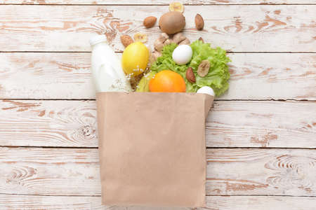 Paper bag with different products on light wooden backgroundの写真素材