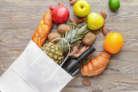 Paper bag with different products on wooden backgroundの写真素材
