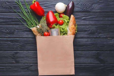 Paper bag with different products on dark wooden backgroundの写真素材