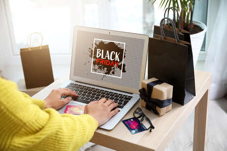 Young woman with laptop shopping online on Black Friday at homeの写真素材