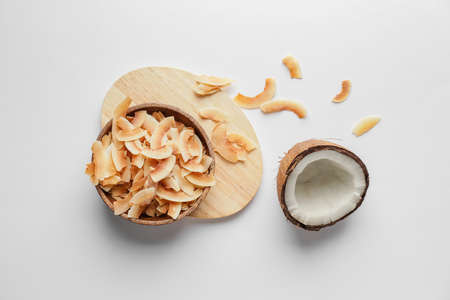 Bowl with tasty coconut chips on light backgroundの写真素材