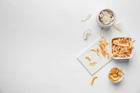 Bowls with tasty coconut chips on light backgroundの写真素材
