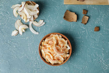 Bowl with tasty coconut chips on color backgroundの写真素材