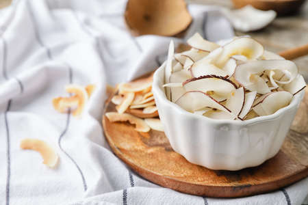 Bowl with tasty coconut chips on wooden backgroundの写真素材