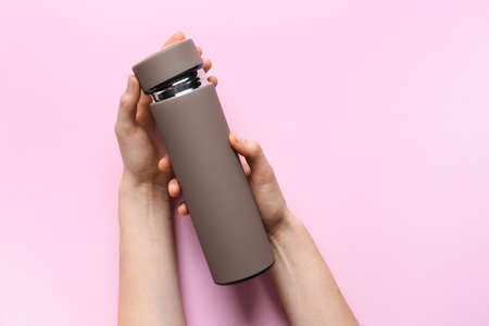 Female hands with modern thermos on color backgroundの写真素材