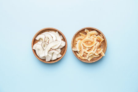 Bowls with tasty coconut chips on color backgroundの写真素材