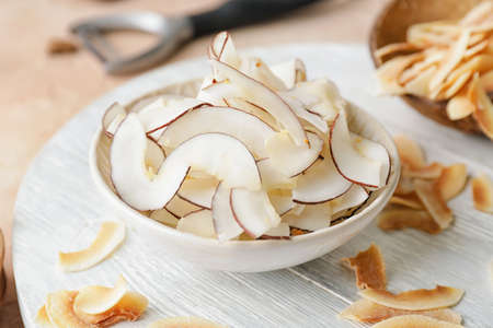 Bowl with tasty coconut chips on tableの写真素材