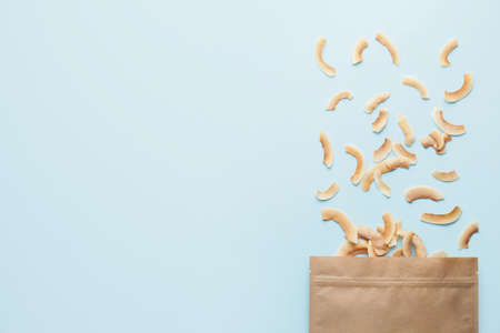 Bag with tasty coconut chips on color backgroundの写真素材