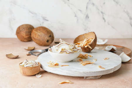 Bowl with tasty coconut chips on tableの写真素材