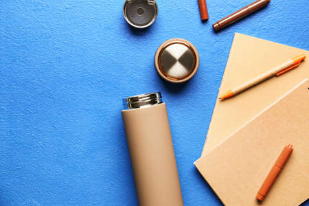Modern flask and stationery on color background