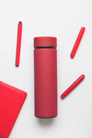 Modern flask with notebook and pens on light backgroundの写真素材