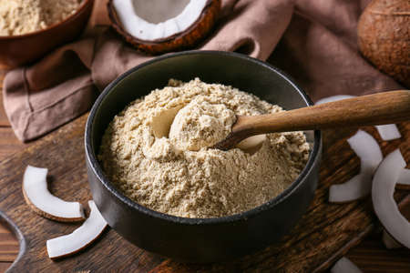 Bowl with coconut flour and spoon on wooden backgroundの写真素材