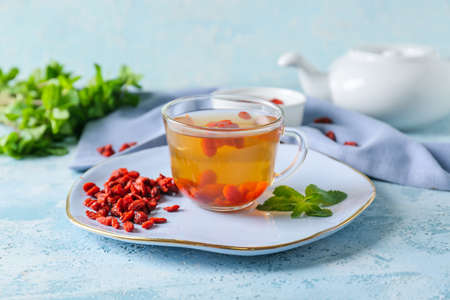 Cup with goji tea on color backgroundの写真素材