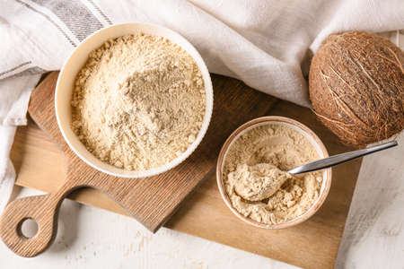 Bowls with coconut flour on light background