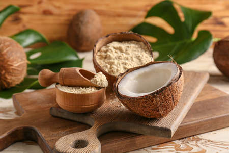 Bowl with coconut flour and scoop on wooden background