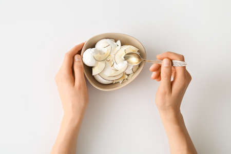 Woman eating tasty coconut ice cream on white background