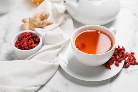 Cup with goji tea on light background