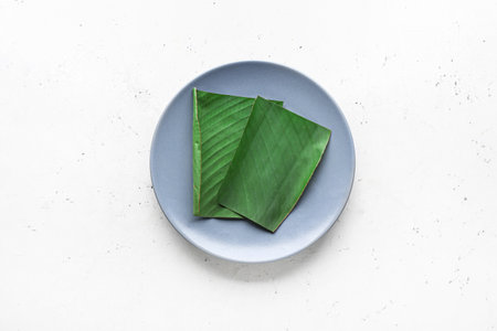Plate with cut banana leaf on white backgroundの写真素材
